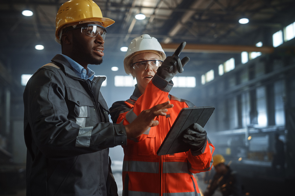 Engineers on tablet in a metal manufacturing factory