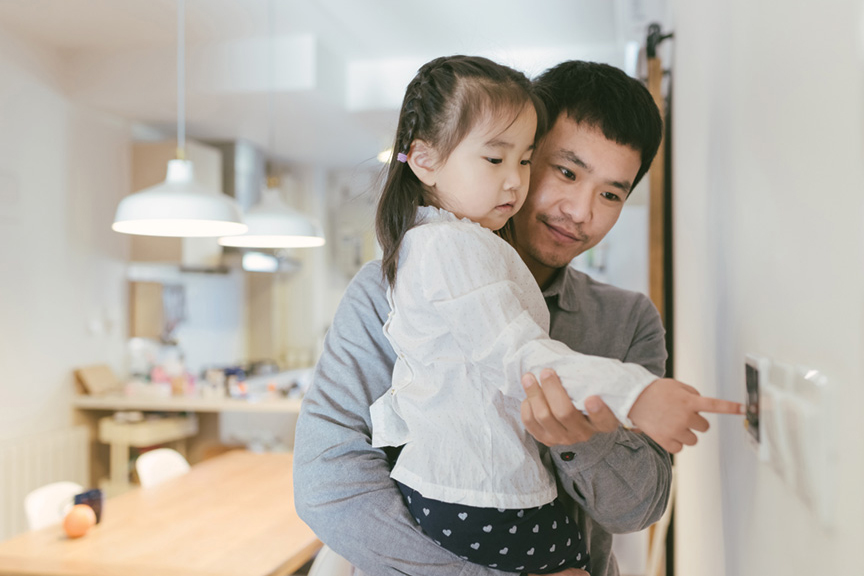 Father holding baby setting thermostat