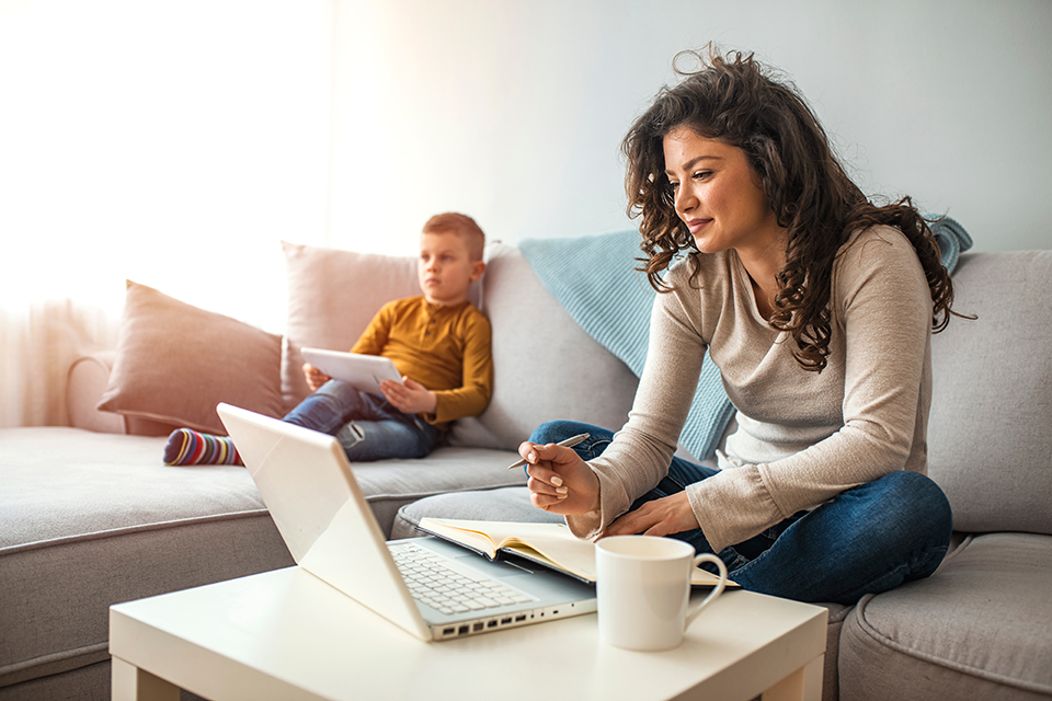 mother working from home on sofa beside young son