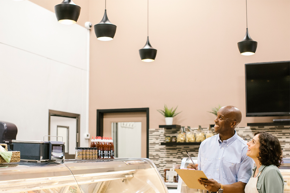 Energy manager and small business owner examining lighting solutions in her cafe