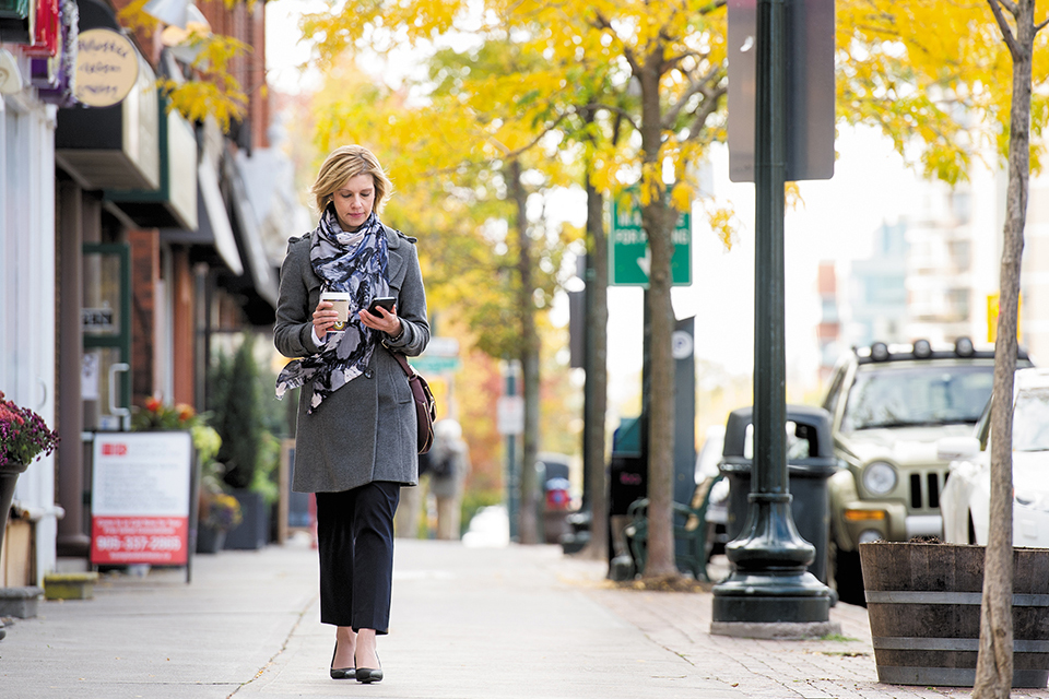 A woman walking down an avenue in autumn